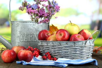 Juicy apples in basket on table on natural background