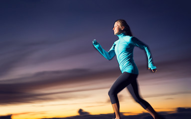 Athletic woman running at sunset dusk with motion blur