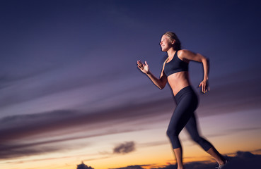 Fototapeta na wymiar Athletic woman running at sunset dusk with motion blur
