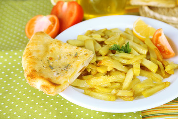 Ruddy fried potatoes on plate on tablecloth close-up