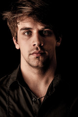 Obraz premium Portrait of pensive young man over black background