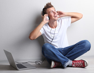 Handsome young man listening to music on grey background