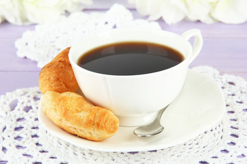 Tasty croissants and cup of coffee on table close-up