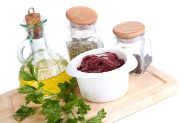 Raw liver in bowl with spices and condiments isolated on white