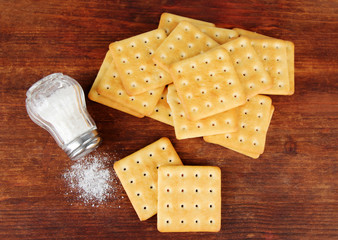 Delicious crackers with salt on wooden background