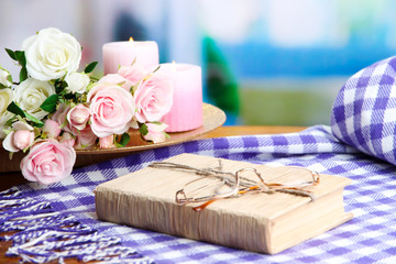 Composition with old book, eye glasses, candles, flowers and