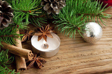 Holiday decoration with candle,fir and cinnamon on wooden backgr