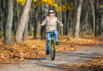 Naklejka premium boy rides a bicycle in park