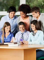 Teacher And Students Discussing Over Mobilephone In Classroom