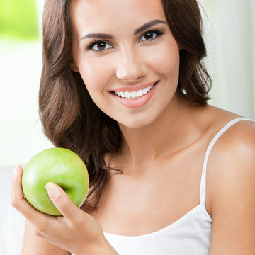 Young happy smiling woman with apple, indoors