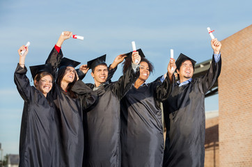 Students With Diplomas Standing Together On University Campus