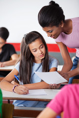 Teacher Showing Paper To Female University Student At Desk