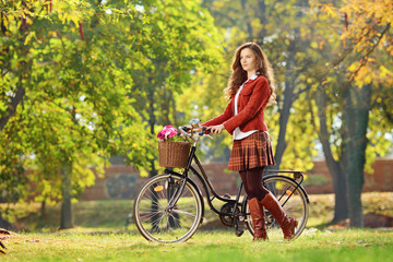 Young female walking with bicycle in park