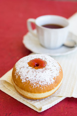 Fresh donut on a napkin with a cup of tea