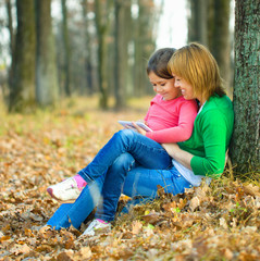 Mother is reading from tablet with her daughter