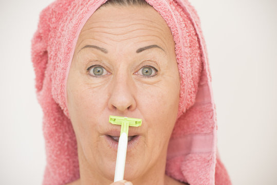 Funny woman shaving face with razor