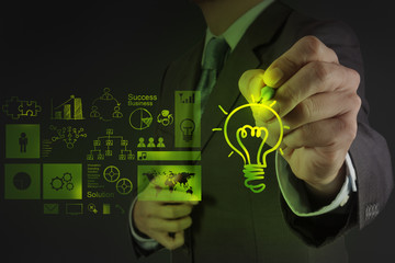 businessman hand draws lightbulb with new computer interface