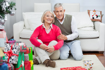 Happy Senior Couple Sitting By Christmas Presents