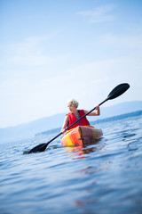 Woman With Safety Vest Kayaking Alone on a Calm Sea