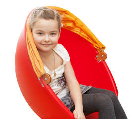 A young girl sits in a red chair
