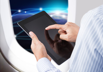 Businessman holding digital tablet in airplane with horizon
