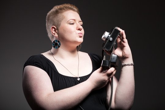 Chubby woman taking pictures of old camera