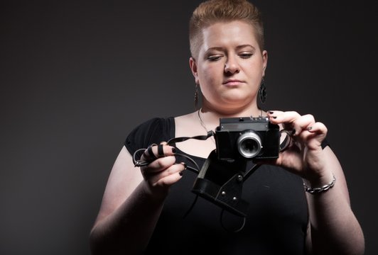 Chubby woman taking pictures of old camera
