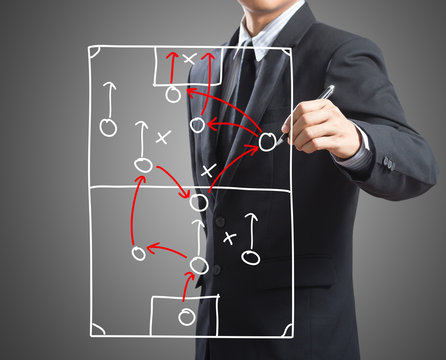 Businessman drawing tactic scheme on board