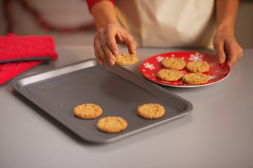 Housewife putting christmas cookies from pan to plate