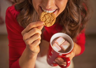 Closeup on happy housewife drinking chocolate and eating cookie - obrazy, fototapety, plakaty