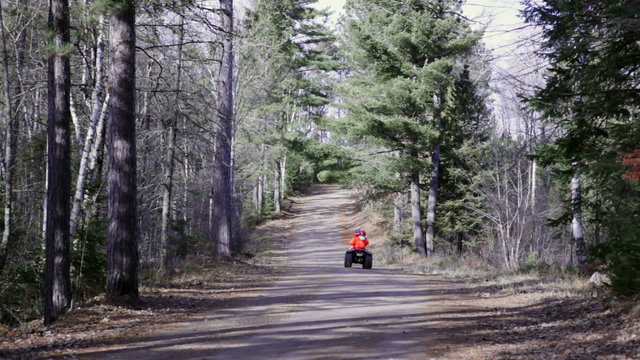 Hunting season - riding four wheeler in woods, blaze orange