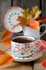 A cup of tea on the table with autumn leaves