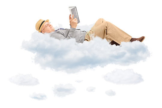 Senior man reading a book and lying on clouds