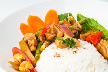 Chicken with rice and vegetables in background