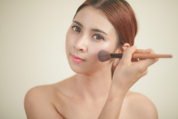 Naklejka premium Young woman applying makeup
