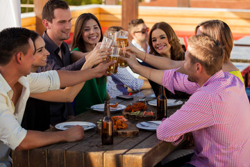 Happy group of friends raising glasses and making a toast to celebrate