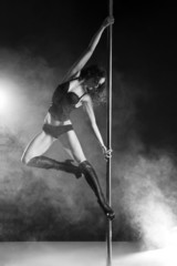 Young slim pole dance woman exercising over dark