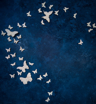 White artificial butterflies over dark blue background © Alex Tihonov