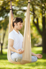 Aerial Yoga, man doing yoga exercises in the park