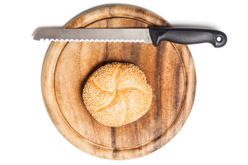 Sesambrötchen und Messer auf Frühtstücksbrett