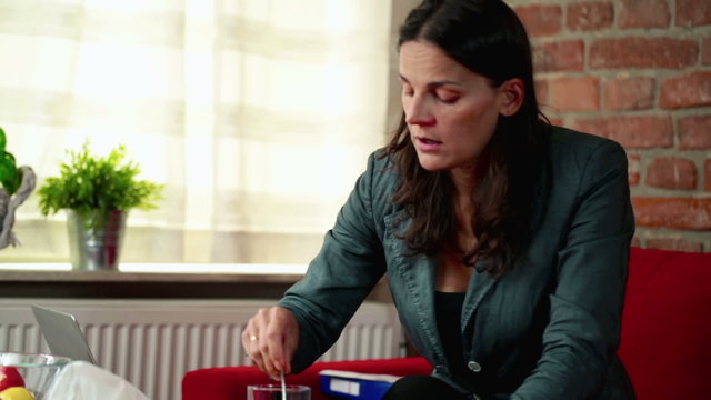 sick businesswoman taking some medicine at home