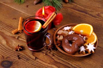 Mulled wine in glass with cinnamon stick, candle and sweets