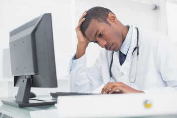 Worried male doctor using computer
