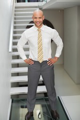 Smiling businessman standing against staircase