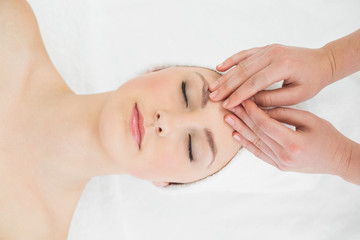 Fototapeta na wymiar Hands massaging a beautiful woman's forehead