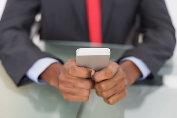 Mid section of well dressed businessman text messaging