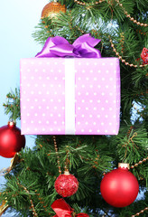 Fototapeta na wymiar Gift on Christmas tree on color background