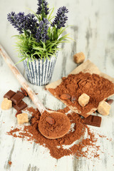 Cocoa powder in spoon on wooden table