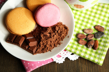 Sweets and cocoa powder on plate on wooden table