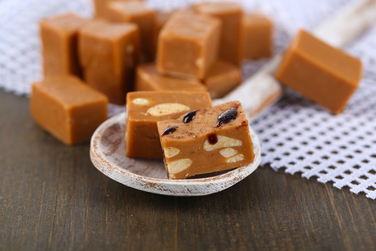 Many toffee in wooden spoon on napkin on wooden table